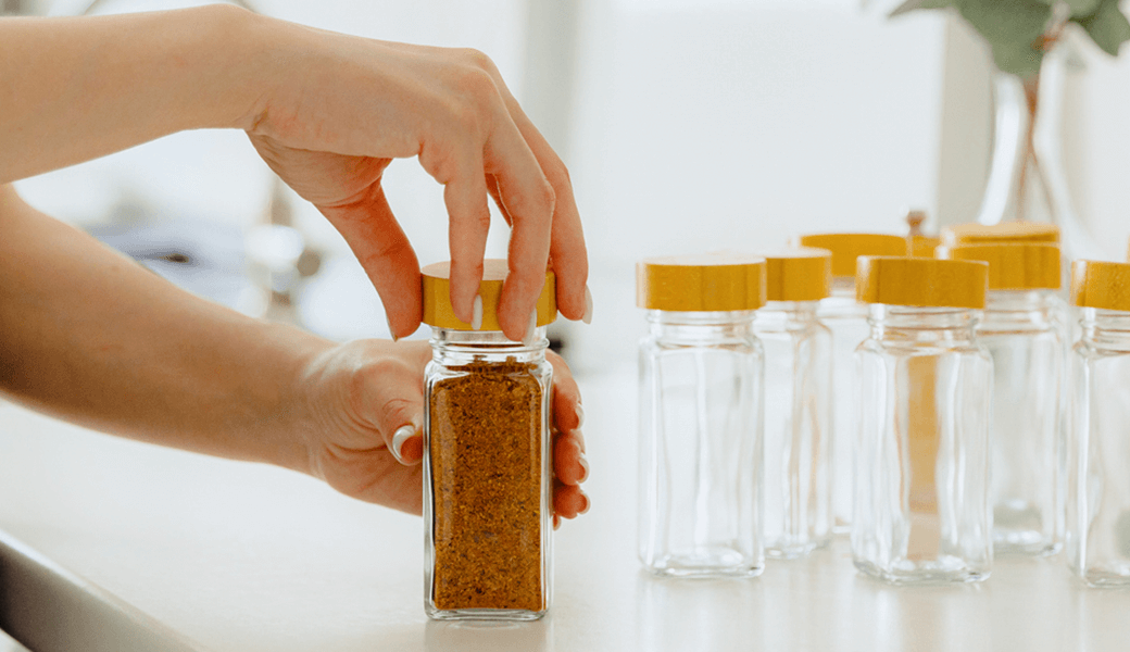 A woman using glass jars to organize spices